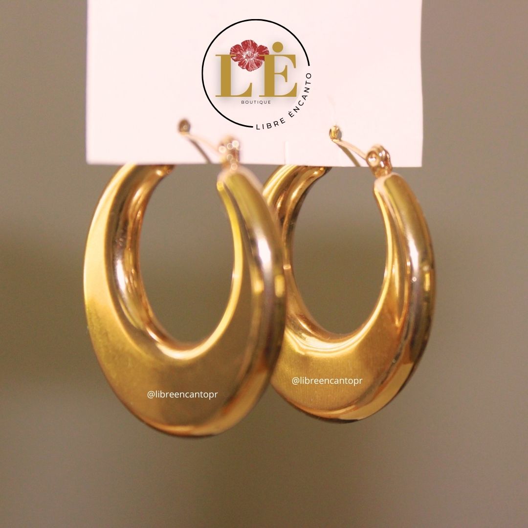 A photo is shown of a pair of gold earrings, 18K gold plated, measuring 3.5 centimeters long and wide. At the top of the earrings the logo of the Libre Encanto boutique is shown, highlighting the maga flower (commonly known in Puerto Rico as Amapola) considered the island's national flower.